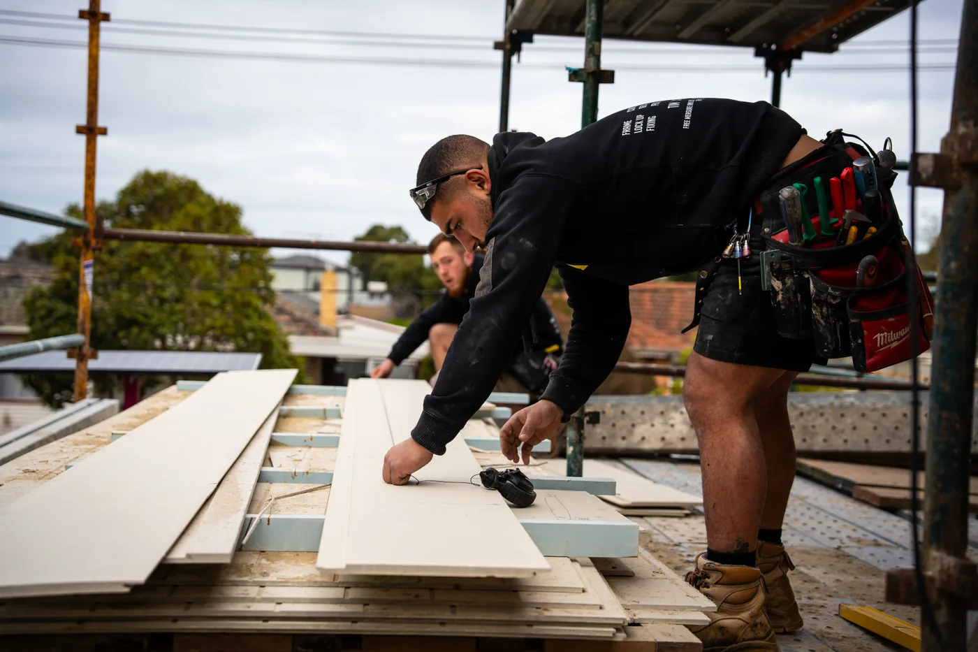 Carpenter measuring and cutting sheet material on a Melbourne construction site