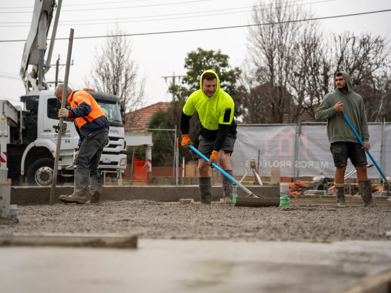 Concrete crew spreading the slab with a concrete pump behind